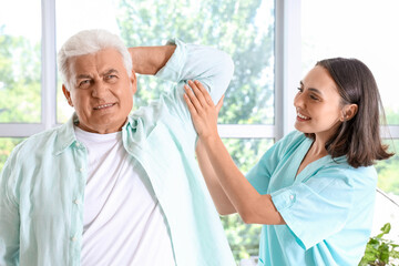 Obraz premium Female physiotherapist working with senior patient in rehabilitation center
