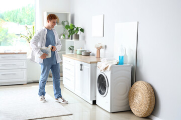 Obraz premium Young man with laundry basket near washing machine