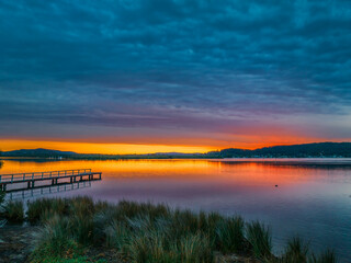 Heavy cloud covered sunrise over the bay with colour and reflections