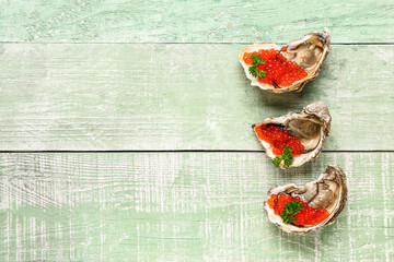 Tasty oysters with red caviar on green wooden background