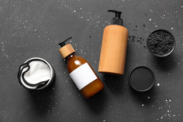 Bottles of shampoo, sea salt and cream on black background - obrazy, fototapety, plakaty