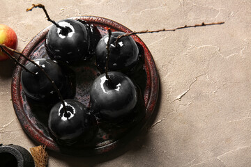 Plate of tasty caramel apples for Halloween on grey background