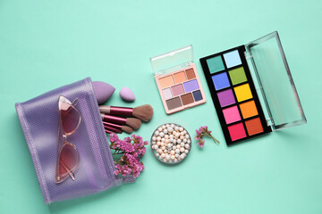 Cosmetic bag with makeup products and beautiful gypsophila flowers on turquoise background