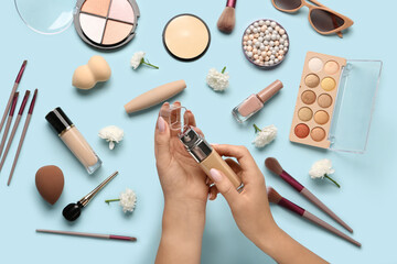 Female hands with bottle of foundation, different makeup products and beautiful chrysanthemum...