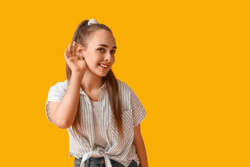 Teenage girl trying to hear something on yellow background