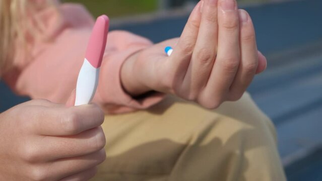 Hold abortion pills. A view of young girl hands with pregnancy test and pill outdoor. A concept of abortion trouble during adolescent time.