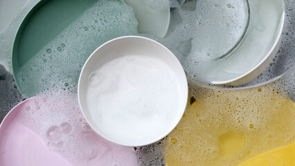 Dishes and bowls in water and bubbles of dishwashing liquid. Kitchen work