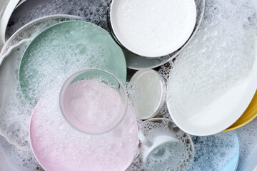 Dishes and bowls in water and bubbles of dishwashing liquid. Kitchen work