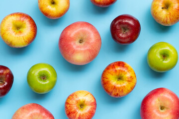 Variety of fresh apples on blue background.