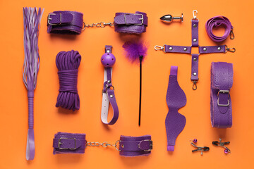 Different purple sex toys on orange background