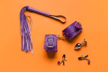 Different purple sex toys on orange background