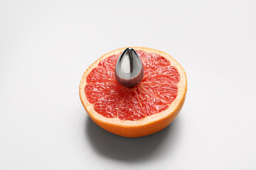 Half of fresh grapefruit with anal plug from sex shop on white background