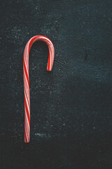 red and white candy cane on black background, top view
