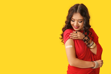 Beautiful Indian woman in sari with medical patch on yellow background - obrazy, fototapety, plakaty