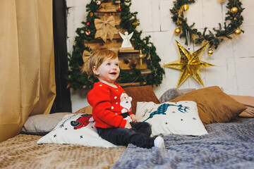 Obraz na płótnie Canvas little one-year-old boy near the Christmas tree. an idea for a children's photo for the new year. studio New Year decoration. Christmas gifts, red children's festive costume