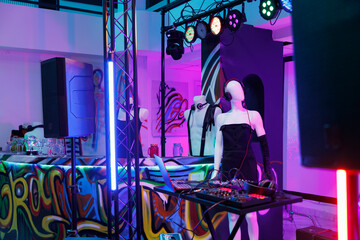 Dj controller and mannequin in headphones on stage in nightclub with spotlights. Musician equipment...