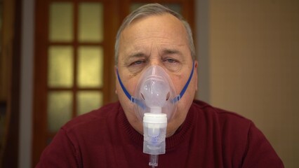 An elderly man inhales through an oxygen mask and looks into the sky. A man does a respiratory...