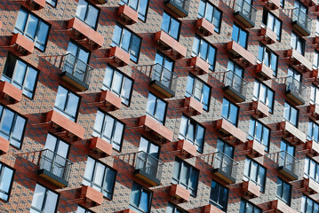 Facade of a modern apartment building with balconies and red brick walls