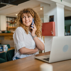 Obraz premium Woman use smartphone make a call talk while work on laptop from cafe