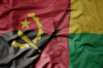big waving national colorful flag of angola and national flag of guinea bissau .