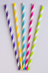 Five stripy coloured paper straws on a white background