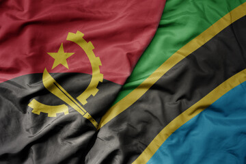 big waving national colorful flag of angola and national flag of tanzania .
