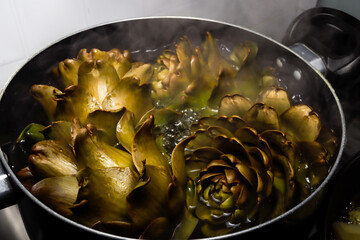 
artichokes cooking in a pot on a gas stove
