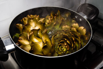 
artichokes cooking in a pot on a gas stove