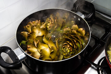 
artichokes cooking in a pot on a gas stove