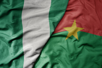 big waving national colorful flag of nigeria and national flag of burkina faso .