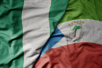 big waving national colorful flag of nigeria and national flag of equatorial guinea .