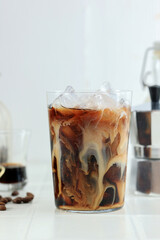 Milk Swirling in a Glass of Black Coffee with Rock Ice