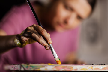 Girl using brush on artistic painting. Female artist creating art.