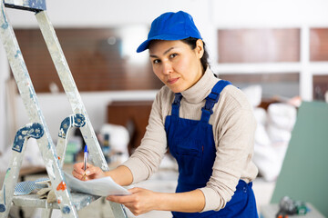 Woman foreman in overalls signs an act of acceptance of completed work