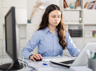 Successful young business woman using laptop at workplace