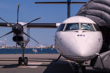 Front view of white modern turboprop airliner with close-up of pointed nose with cockpit windows,...
