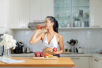 Healthy Asian woman in exercise clothes Is happily cooking a healthy meal in her home kitchen in...