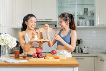 Two healthy Asian female friends in exercise clothes  Is happily cooking a healthy meal in her home...