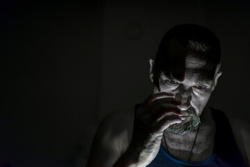 Close up of sad man in dark room. Depression and anxiety disorder concept.