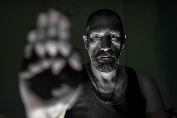 Portrait of a young sad man showing his hand. Stop sign.