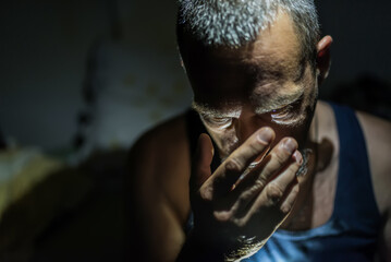 Close up of sad man in dark room. Depression and anxiety disorder concept.