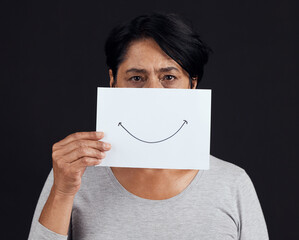 Portrait, fake smile or depression and a mature woman in studio on a dark background with an...