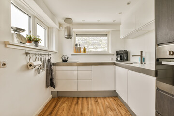 a modern kitchen with wood flooring and white cabinets in the room is well lit by the light coming through the window