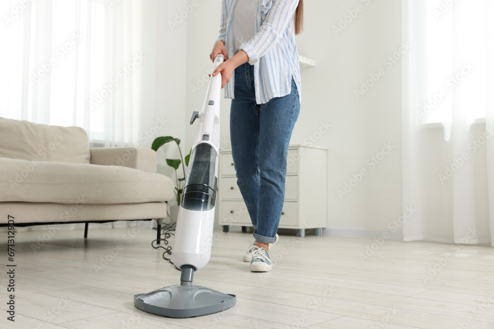 Wall mural Woman cleaning floor with steam mop at home, closeup