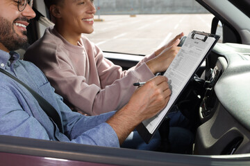 Driving school. Student passing driving test with examiner in car at parking lot, closeup - obrazy, fototapety, plakaty