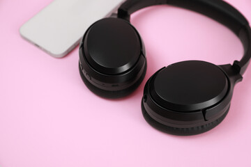 Obraz na płótnie Canvas Modern wireless headphones and smartphone on pink background, closeup