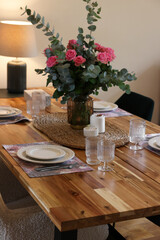 Beautiful table setting with bouquet and candles indoors. Roses and eucalyptus branches in vase