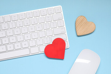 Long-distance relationship concept. Keyboard, computer mouse and decorative hearts on light blue background, flat lay