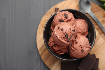 Bowl with tasty chocolate ice cream on wooden board, flat lay. Space for text