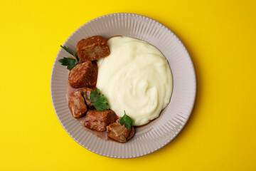 Delicious goulash with mashed potato on yellow background, top view